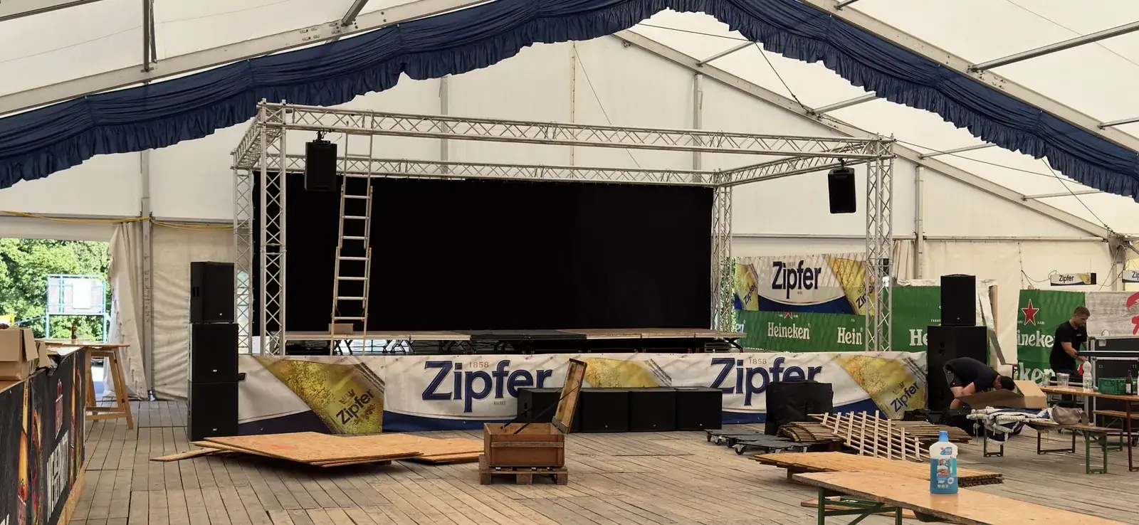 Festzelt beim Kirtag Ampflwang während des Aufbaus: Bühne mit Traversengerüst, hängende Lautsprecher, Subwoofer und Boxen links und rechts