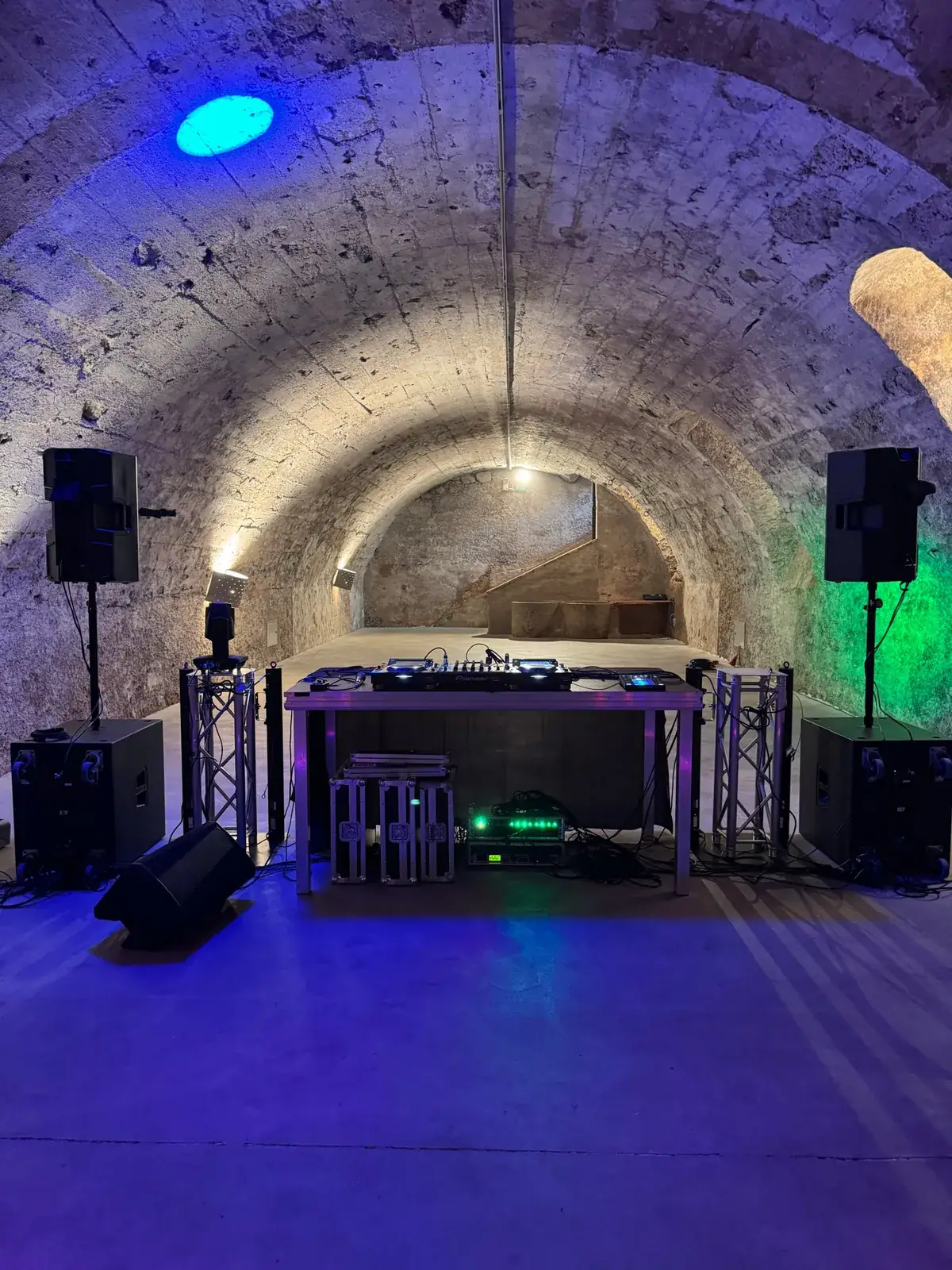 DJ-Pult mit Pioneer-Technik, Lautsprechern auf Stativen, Subwoofern und Traversen im beleuchteten Gewölbekeller von Schloss Tillysburg