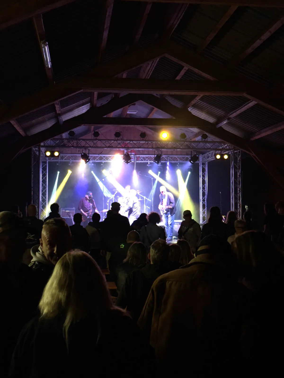 Hausrock 2026: Band im Licht von Moving Heads, Publikum im Vordergrund unter dem Dachstuhl