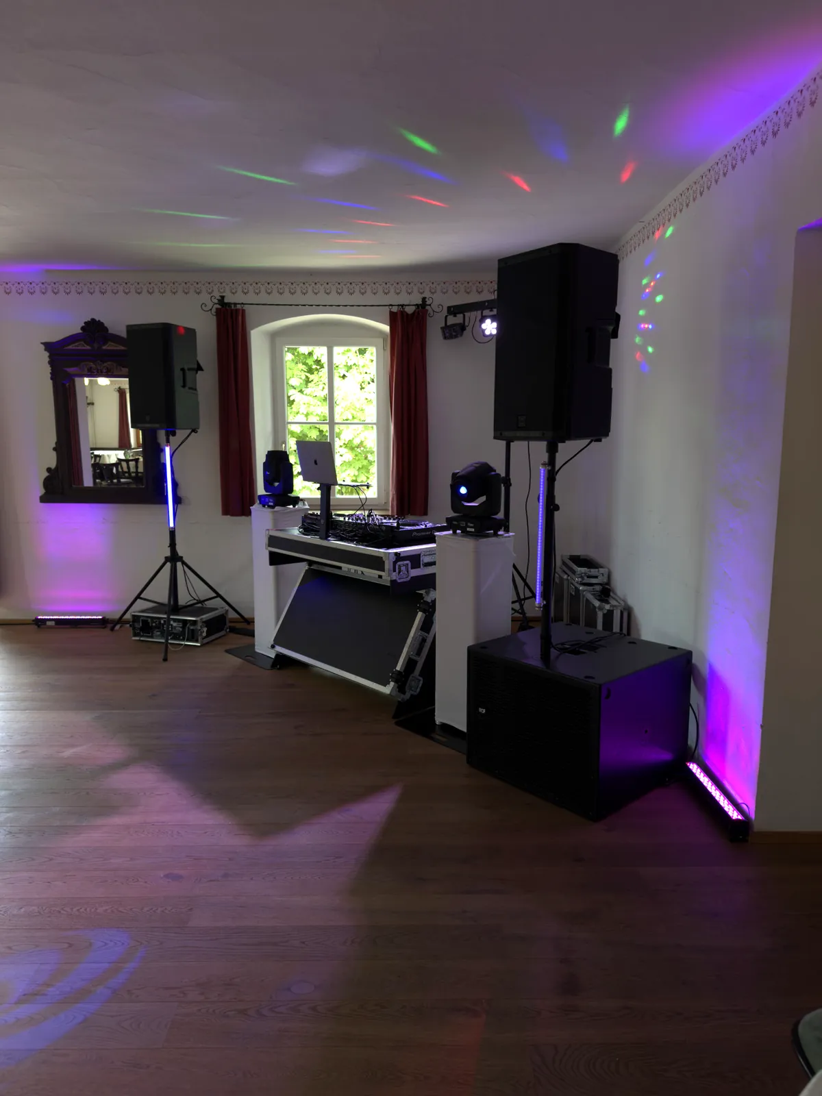 Saal in einem Wirtshaus vor einer Hochzeit: DJ-Pult, Lautsprecher auf Stativen, Subwoofer und farbige Lichtpunkte an der Decke
