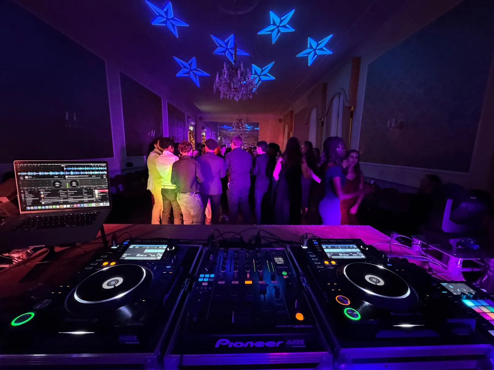 Blick über Pioneer DJ-Player und Mischpult auf die Tanzfläche beim Maturaball der HBLW Linz, blaue Sterne an der Decke